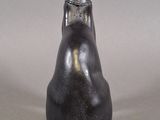 sculpture of a cat sitting on its hind legs with a collar around it ' s neck