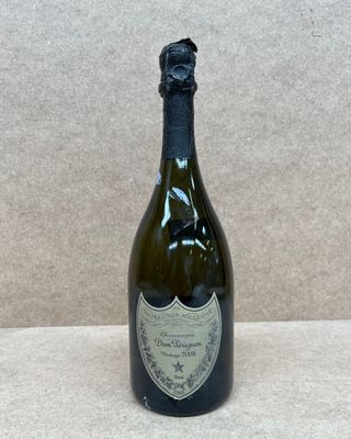 une bouteille de vin posée sur une table à côté d'un mur