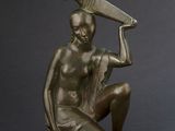 bronze statue of a seated woman holding a bottle and a bottle of wine
