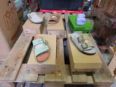 Plusieurs paires de sandales sont posées sur une palette dans un entrepôt.