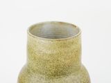 a green vase that is sitting on a white surface
