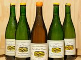 Plusieurs bouteilles de vin sont alignées sur un tonneau en bois