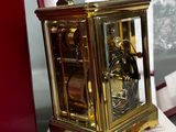 a gold clock sitting on top of a table next to a red box