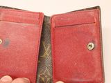 a hand holding a red wallet with a button on it