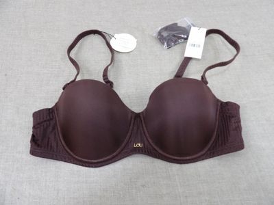 une bralette marron posée sur un lit, avec une étiquette de prix