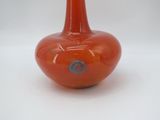 an orange vase with a blue dot on it