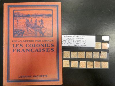 un livre orange posé sur une table noire, à côté d'une pile de timbres