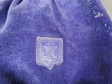 blue velvet drawsack with a badge on it sitting on a table
