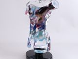 a glass sculpture of a male torso on a black base