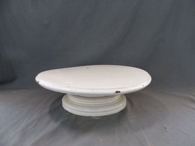une assiette à gâteau blanche posée sur une table, sur fond gris
