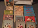 Plusieurs livres pour enfants sont alignés par terre, à côté d'une étagère
