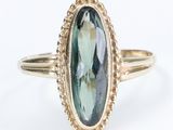 a close up of a gold ring with an oval green tourmaline