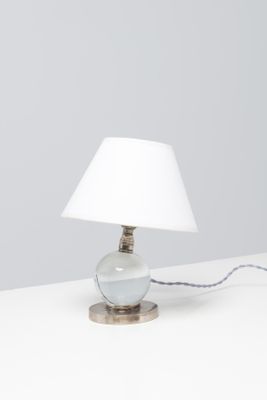 une lampe de table surmontée d'un abat-jour blanc, posée sur une surface blanche