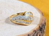 a gold ring with two diamonds on it on a wood slice