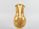 yellow vase with gold decoration on base on grey background