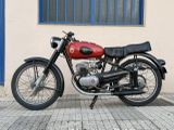 a red motorcycle parked on the sidewalk in front of a building