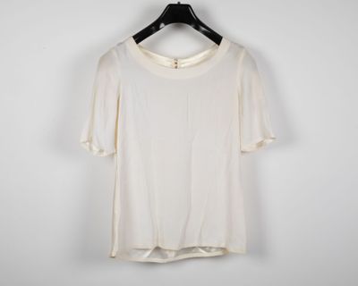 a white t - shirt hanging on a hanger against a white wall