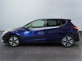 a blue nissan versa parked in a room with a white wall