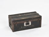 une vieille valise posée sur une surface blanche