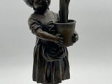 une statue en bronze représentant un garçon tenant un pot de fleurs