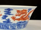 a blue and white bowl with a red dragon on it