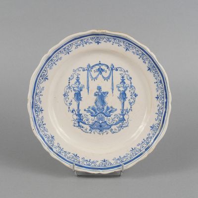 une assiette ancienne bleue et blanche représentant un homme et une femme dans un jardin