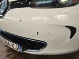 a white car that has been dented and is parked in a garage