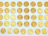 a large collection of gold coins on a white surface