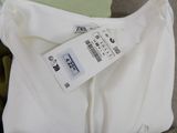 a white shirt with a tag on it sitting on the floor
