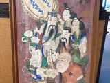 tableau encadré représentant un groupe de personnages asiatiques, exposé dans une pièce