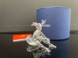 figurine en cristal représentant une femme assise sur une table, à côté d'une boîte bleue