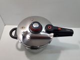 a silver pot with a red handle on a white surface