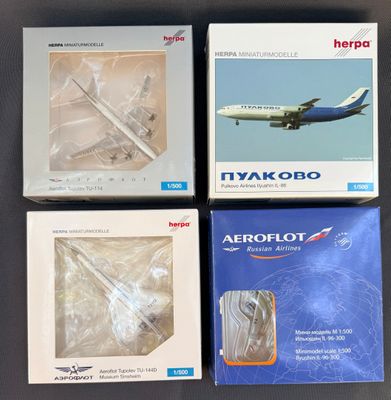 quatre livres dans leur boîte posés sur une table, avec un avion en arrière-plan