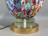 a multicolored glass ball on a gold base