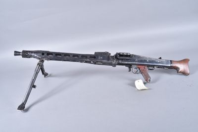 an old machine gun with a wooden barrel on a white surface