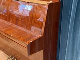 a piano that is sitting on the floor in front of a curtain