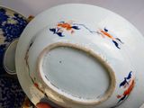 a person holding a blue and white bowl with orange flowers on it