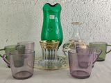many different colored glassware on a table with a green vase