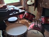 une batterie installée dans un salon, à côté d'un piano