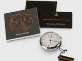 a close up of a pocket watch with a business card on a table