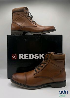 men ' s brown leather boots on display in front of a box