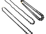 trois colliers composés de perles noires et une paire de boucles d'oreilles