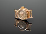 une montre-bracelet en or posée sur une surface noire