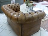 a brown leather couch sitting on a tile floor in a room