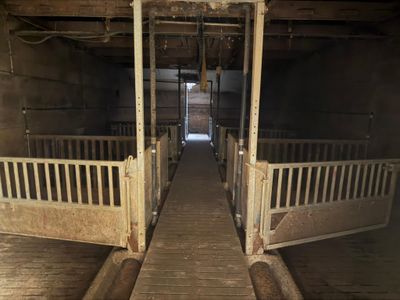 a long wooden walkway leading to two stalls in a barn