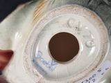 a person holding a fish shaped vase with a tag on it