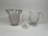 trois verres posés sur une table, à côté d'un pichet et d'un verre à pied