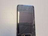 someone is holding a broken cell phone on a white surface