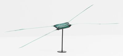 une sculpture en verre posée sur un socle métallique, sur une surface blanche