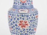 un vase bleu et blanc orné de fleurs rouges